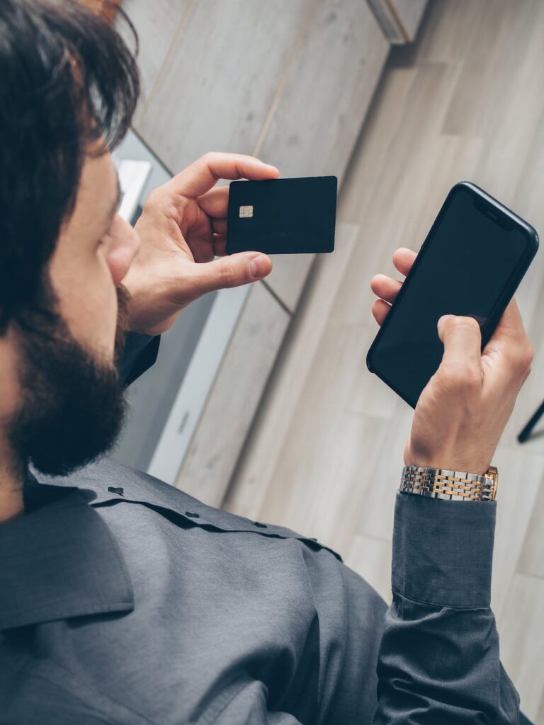 man in gray sweater holding black smartphone