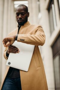 man in brown overcoat looking at the time