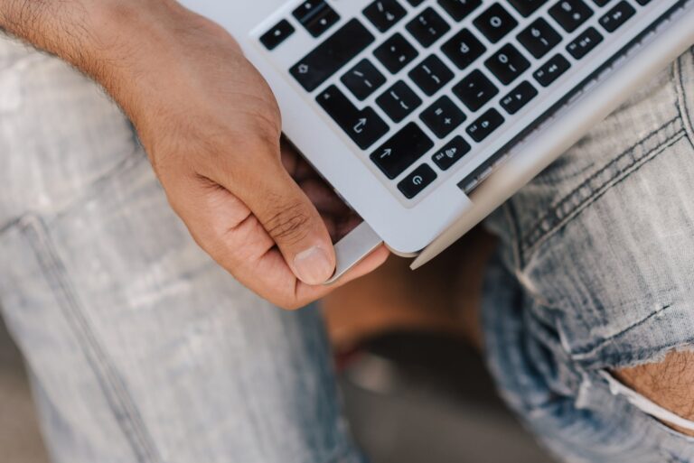 crop unrecognizable man inserting flashcard into laptop slot