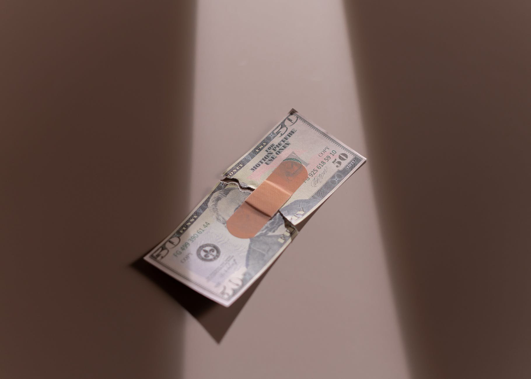 a bandage on a ripped fifty dollar bill