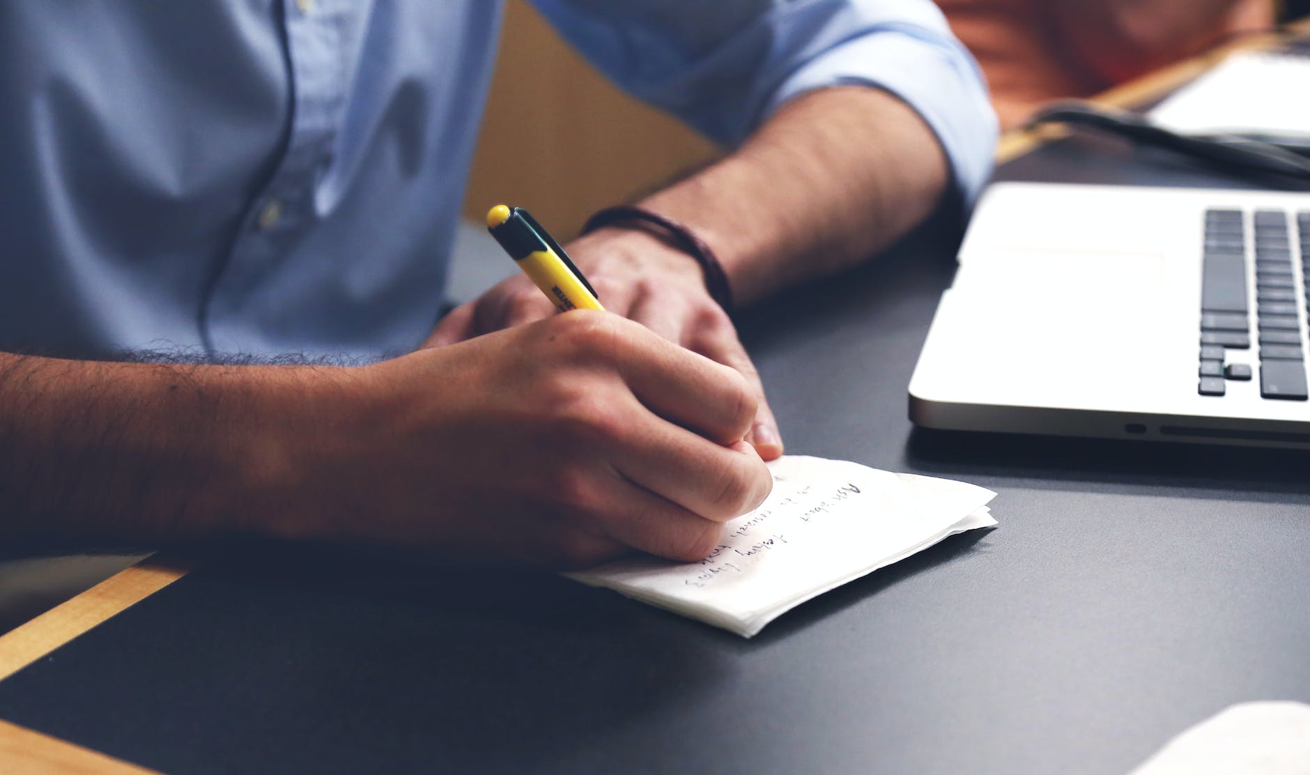 person writing on paper using yellow and black pen